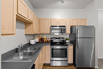 A kitchen with stainless steel appliances including microwave and dishwasher, and light oak cabinetry with lots of storage.